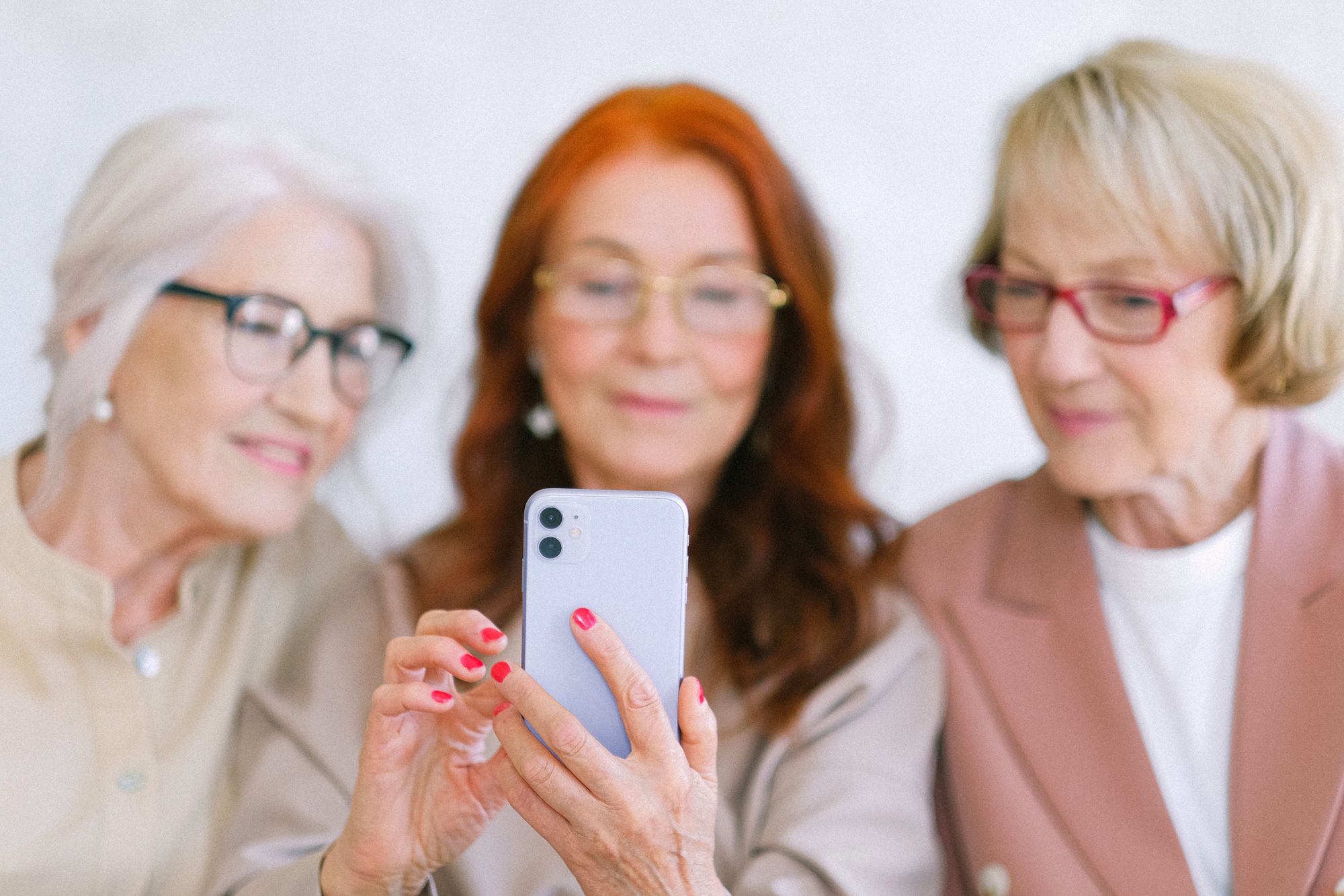 Three women smiling as they look at a smartphone together
