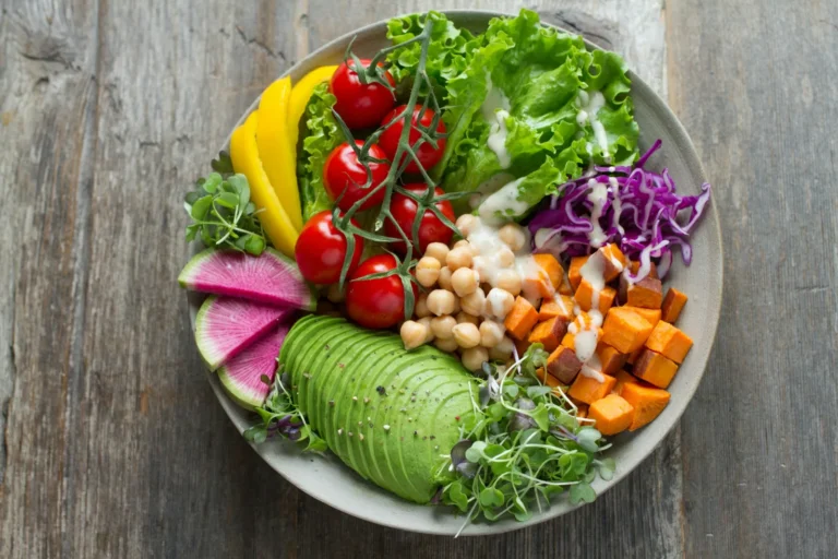 A bowl with avocado, chickpeas, roasted sweet potato, tomatoes, red cabbage and leafy greens